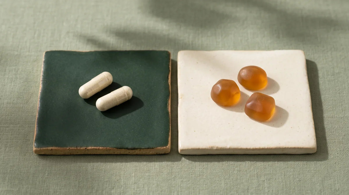 Cream-colored capsules and amber gummies on contrasting ceramic tiles.